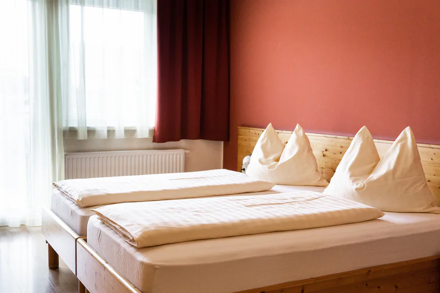 Zimmer mit zwei Betten und roter Wand